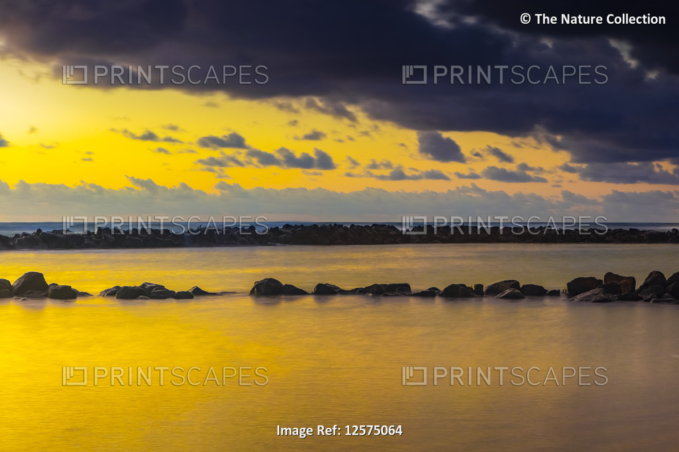 Golden sunrise over Lydgate Park and the ocean from the coast of Kauai with a ...