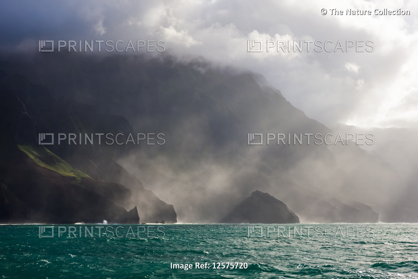 Sunlight shines through the fog along the Na Pali Coast, Kalalu Valley; Kauai, ...