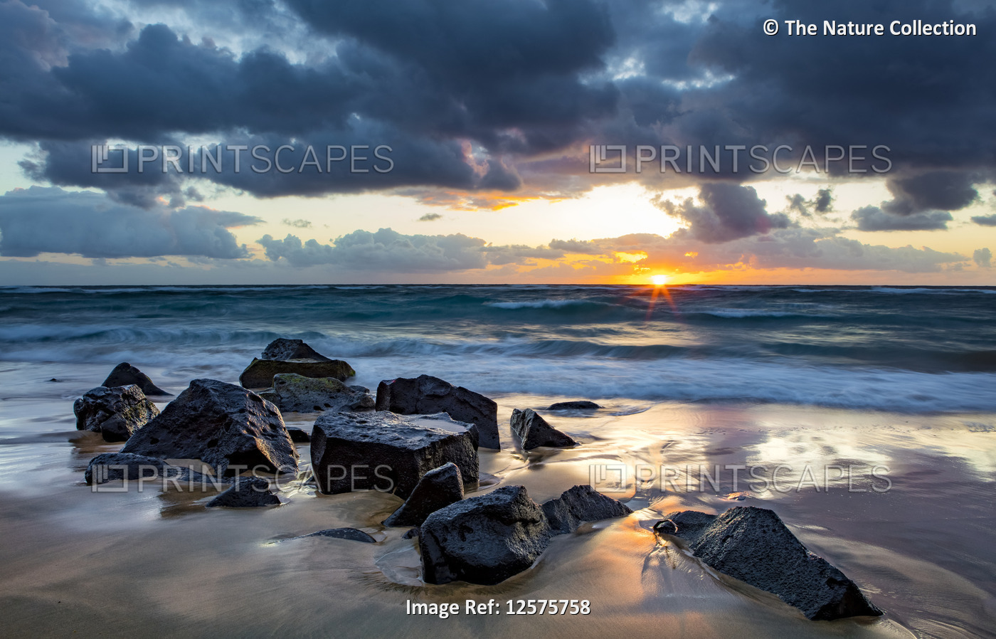 Sunrise over the Pacific Ocean from the rocks on the shore of Lydgate Beach and ...