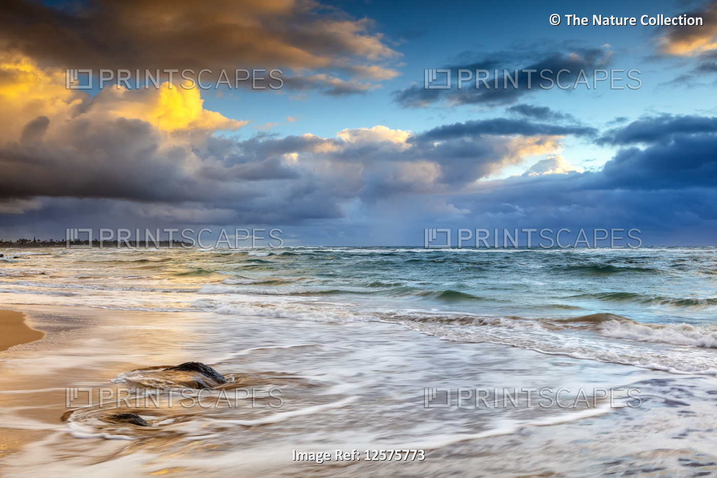 Sunrise over the Pacific Ocean from the shore of Kauai and dark clouds over the ...