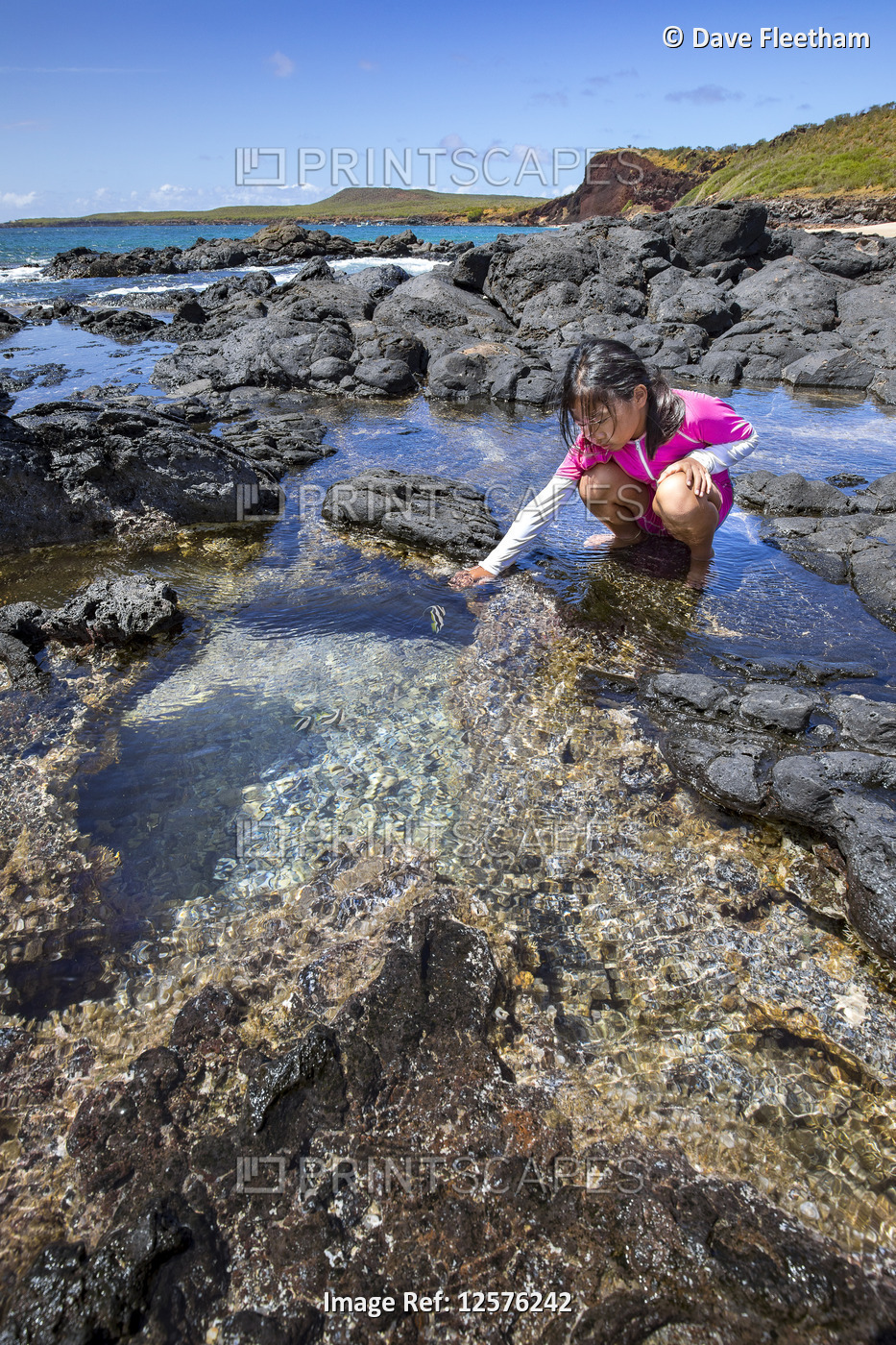 A young girl examines life in a tide pool beside Kawakiu Nui Beach on Molokai's ...
