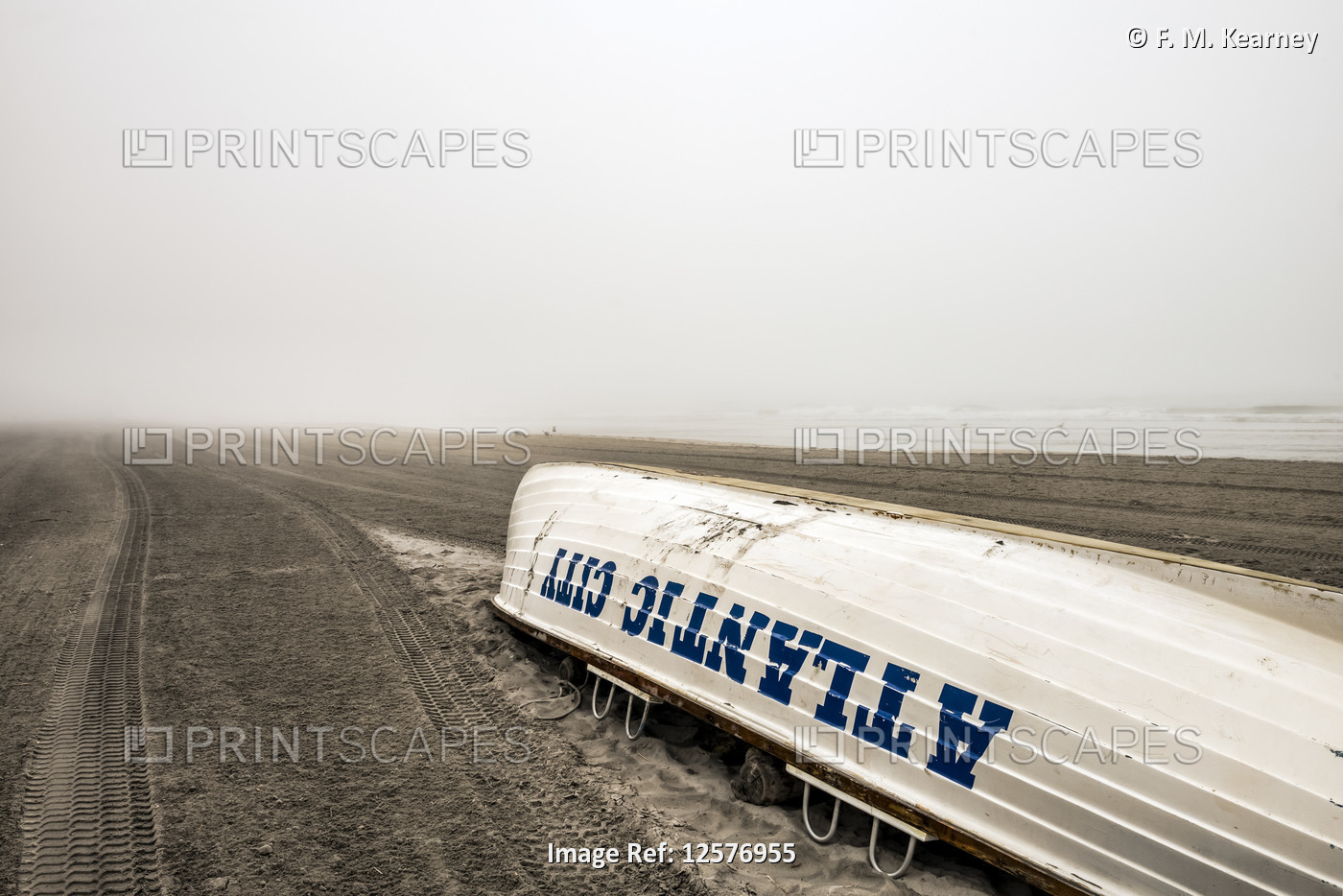 Foggy conditions on Atlantic City beach with an overturned boat on the sand; ...