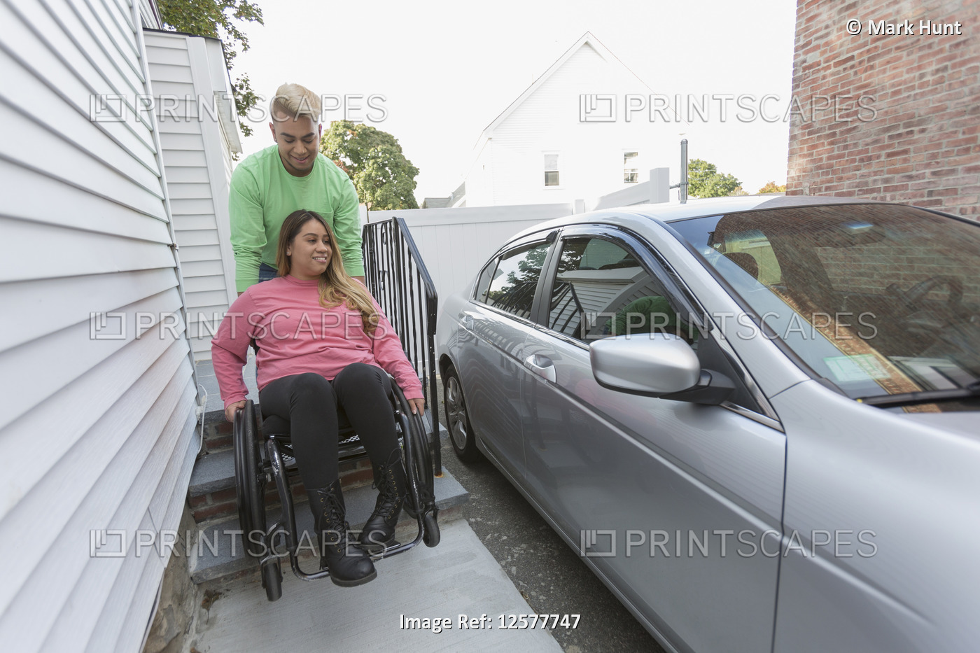 Man assisting a woman who has Spinal Cord Injury getting into her car