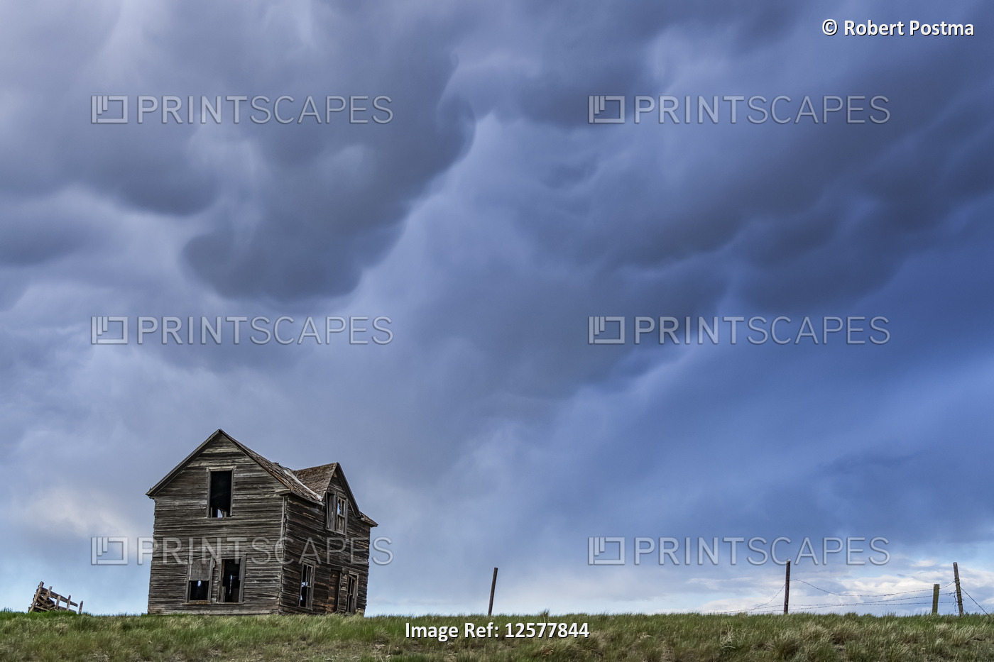 Old farmstead on the prairies under a stormy sky; Saskatchewan, Canada
