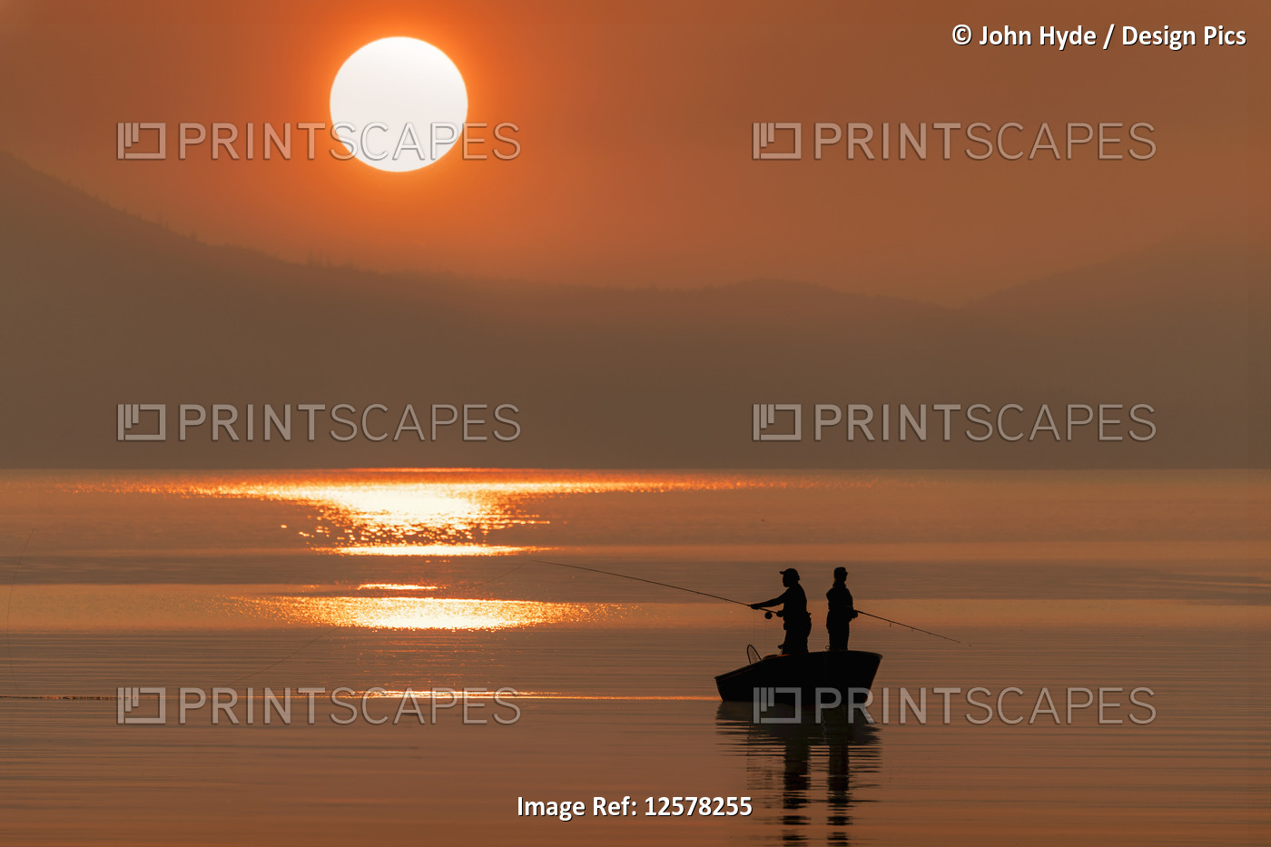 Silhouetted anglers standing in a boat fishing for salmon at sunset; Juneau, ...