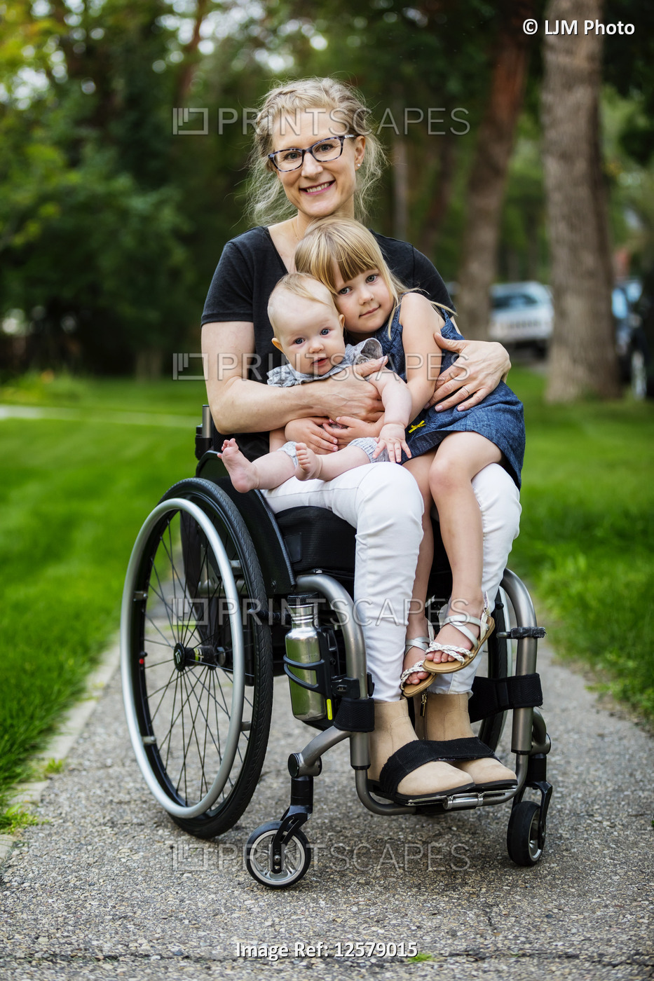 A paraplegic mom carrying her daughters on her lap while using a wheelchair ...