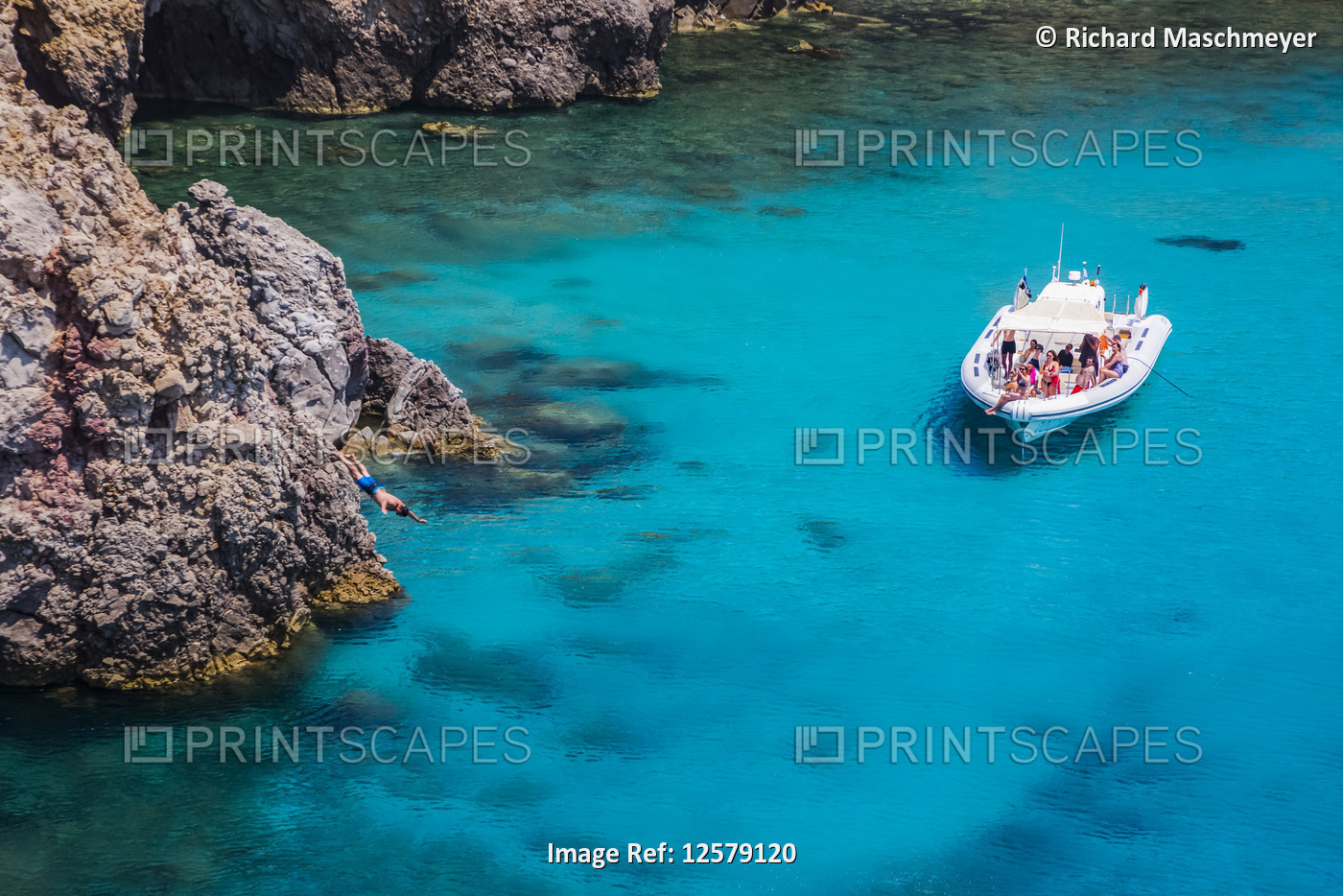 Tourists on a tour boat at Tsigado Beach, with a young man diving off a cliff; ...