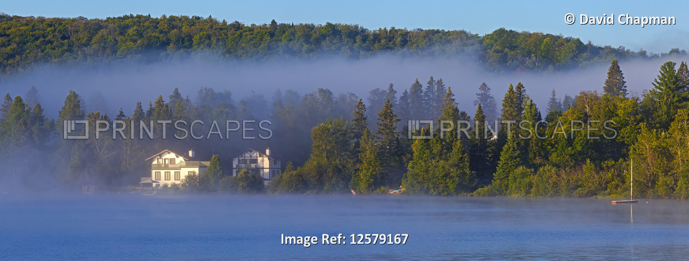 Mist lays over Lac a la Truite at dawn with low cloud hanging over the forest ...