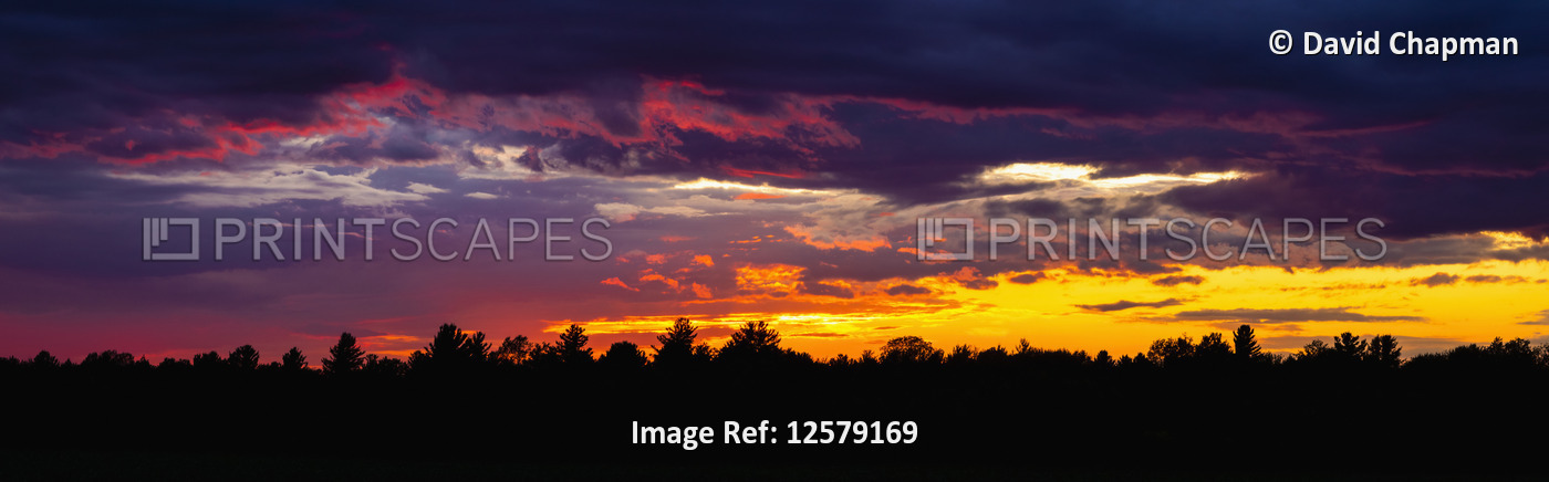 Dramatic sky at sunset with dark clouds and colourful light glowing above ...