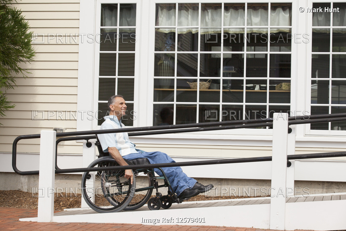 Man in a wheelchair on a ramp accessing a building