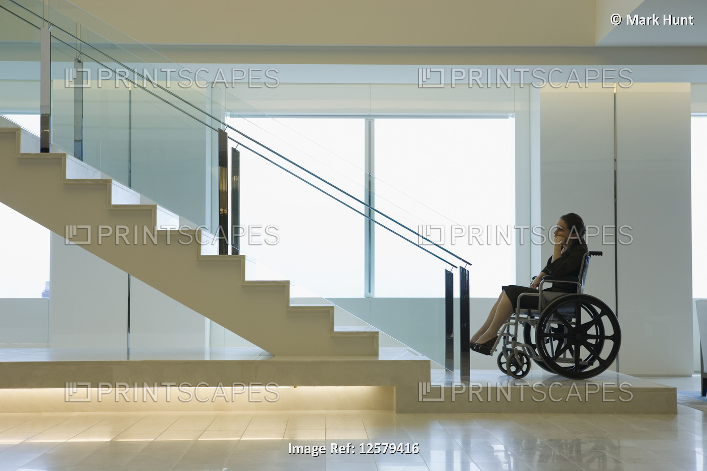 Side profile of a businesswoman on a wheelchair near a staircase
