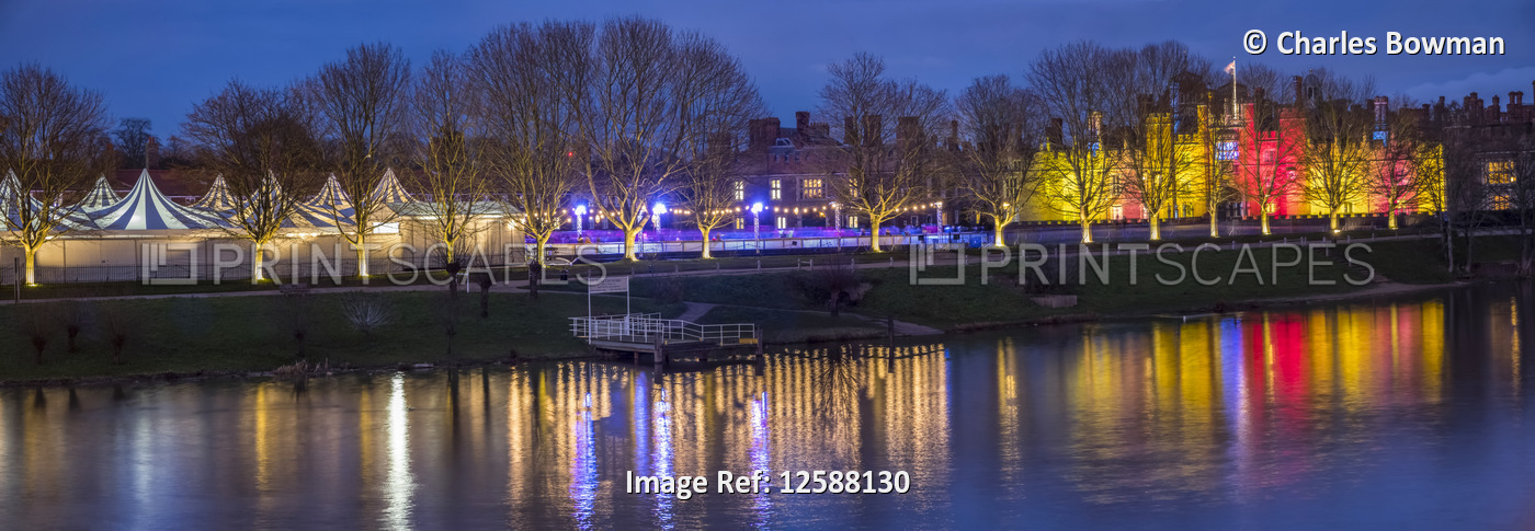 Hampton Court with Christmas lights glowing and reflected in the water; London, ...