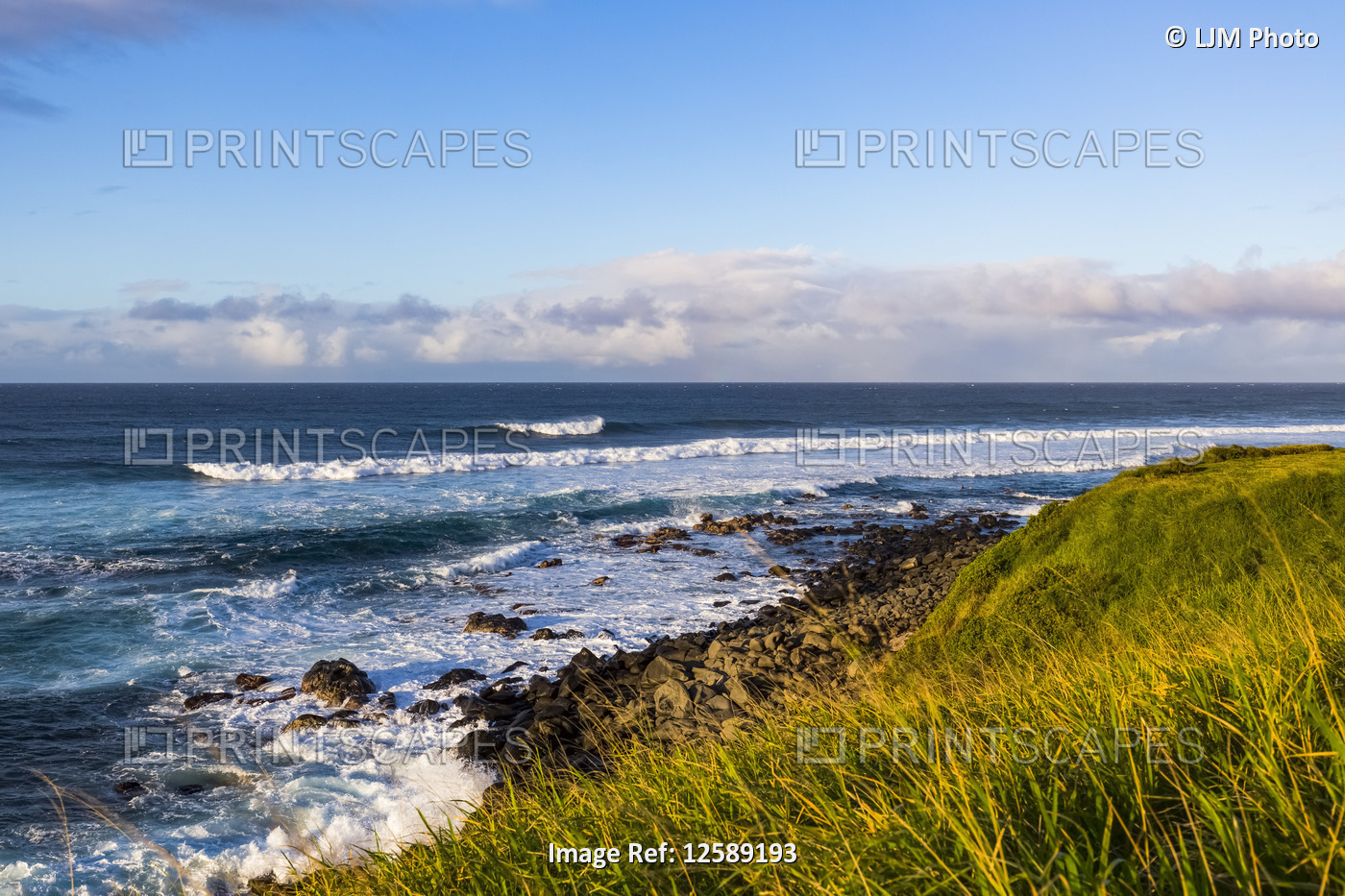 Ocean waves cresting and rollling into the rock and grassy shore at sunset with ...