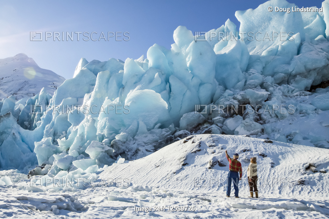 Hikers on the edge of frozen Portage Lake and looking at the Portage Glacier ...
