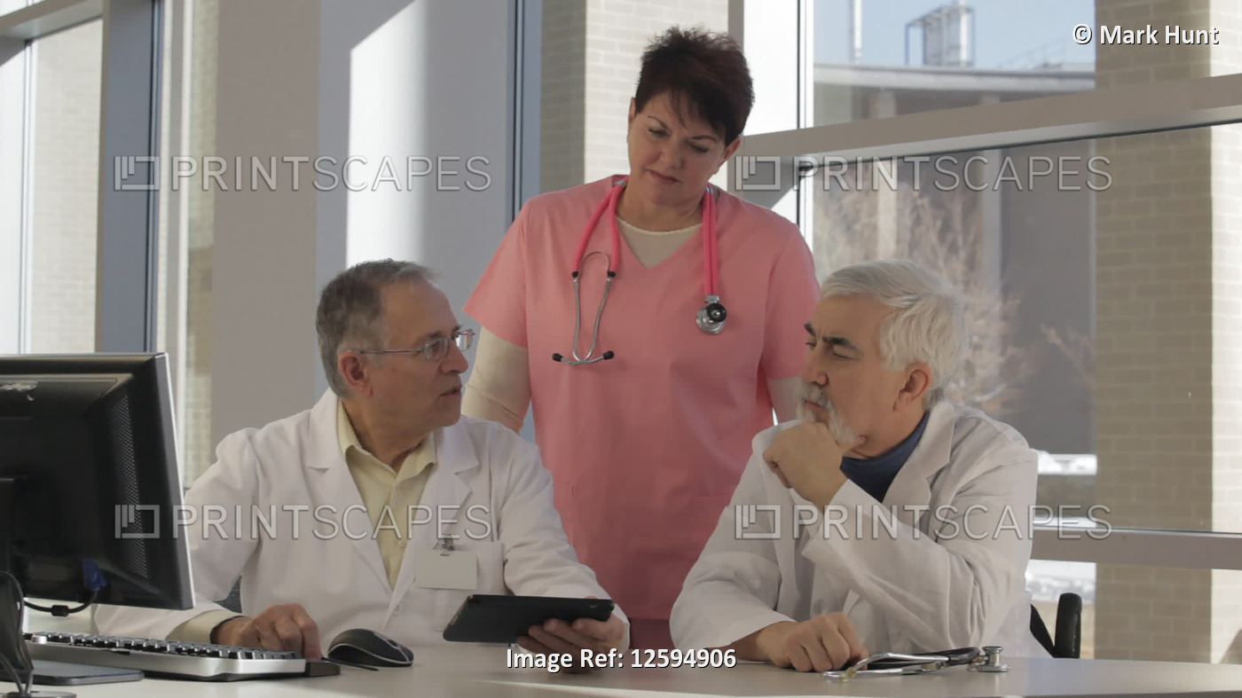 Two doctors and a nurse using a computer and tablet, one doctor with Muscular ...
