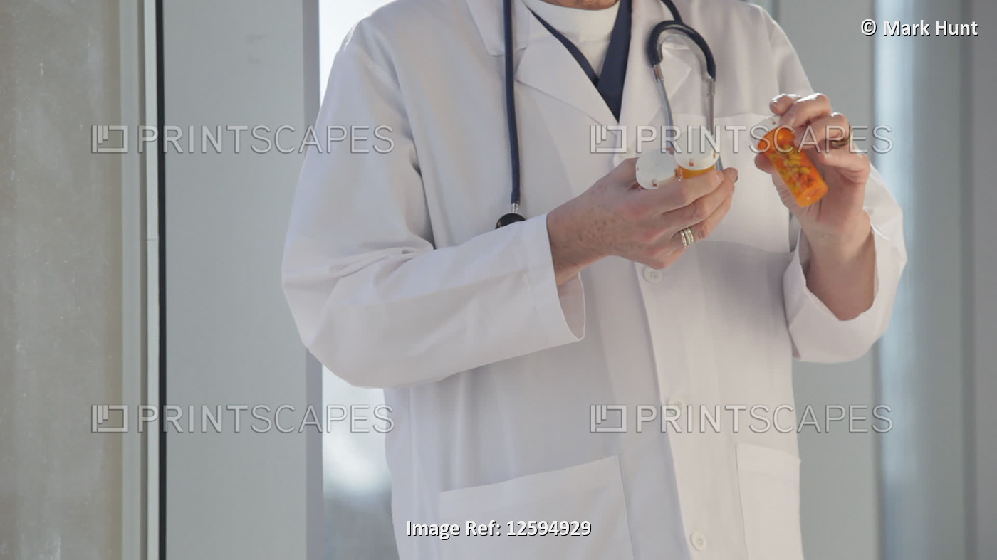 Doctor looking at pills in bottles; United States of America