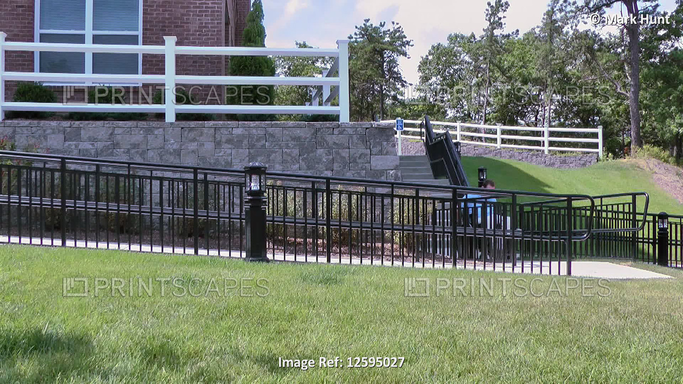 Man with spinal cord injury in a wheelchair using accessible wheelchair ramp ...