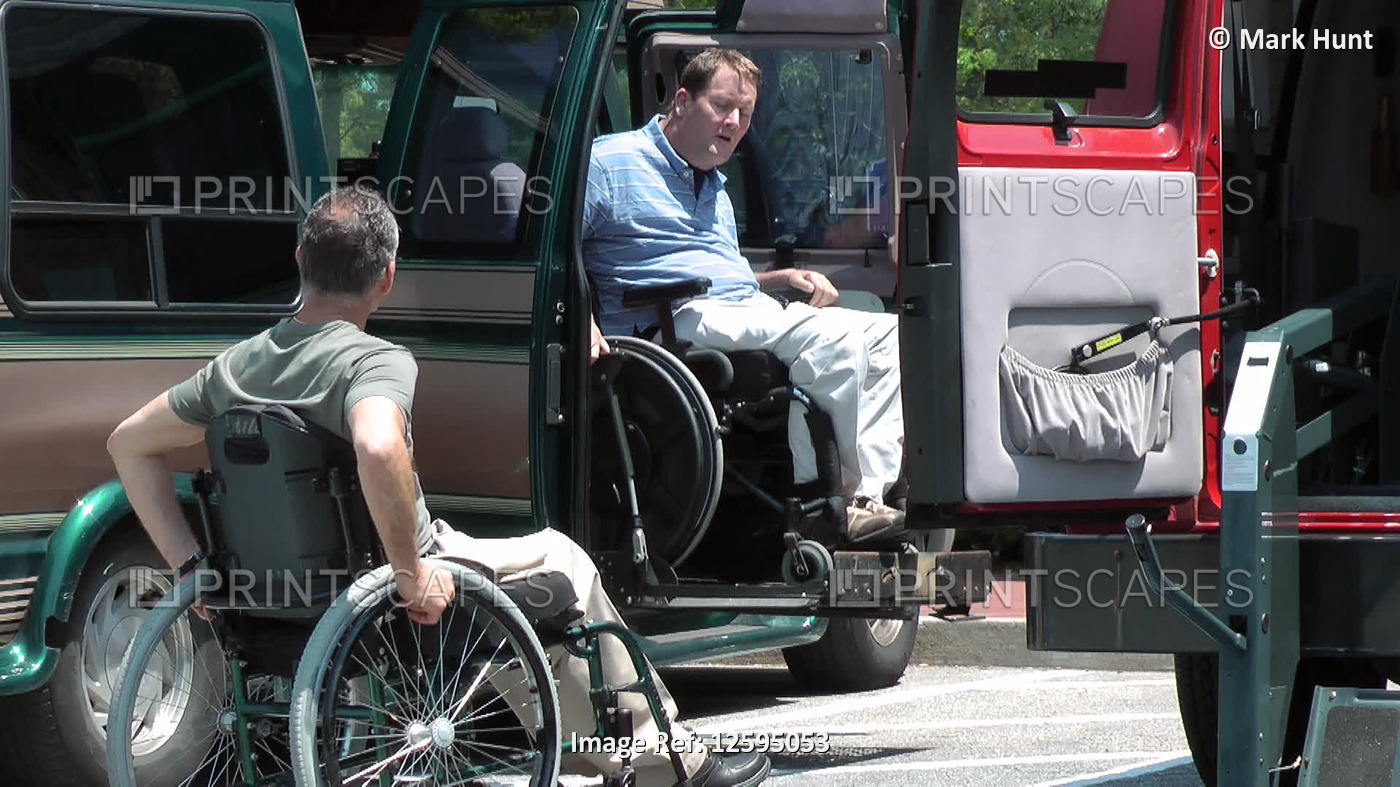 Two men with spinal cord injuries in wheelchairs, one entering accessible van; ...