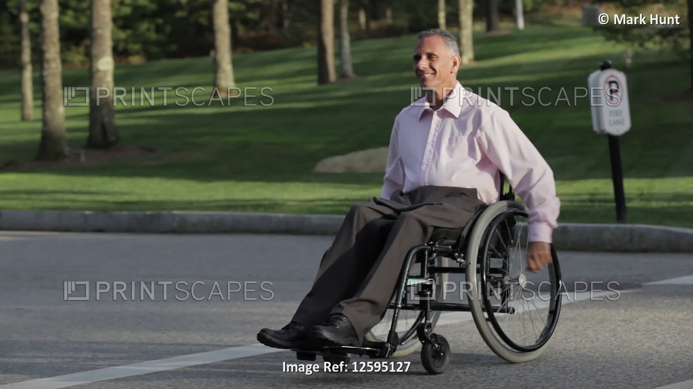 Man with spinal cord injury in a wheelchair crossing street at accessible ...