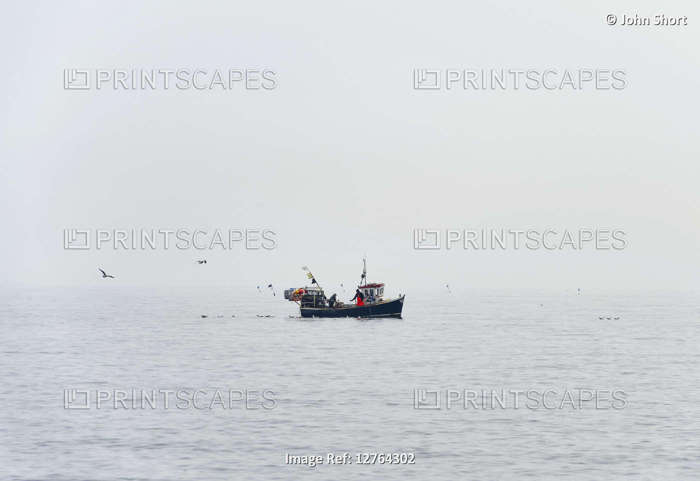 Fishing boat on the ocean in foggy conditions with seagulls flying and swimming ...