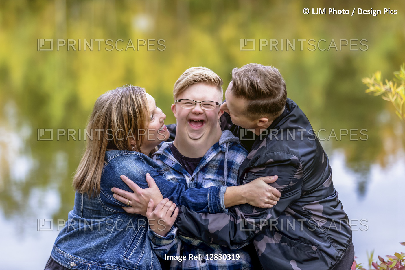 A young man with Down Syndrome being teased and hugged by his father and mother ...