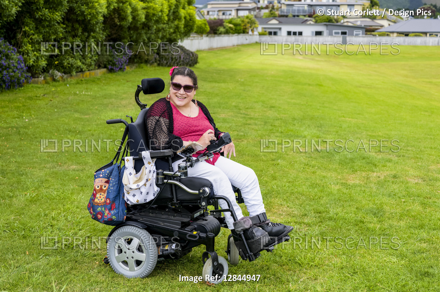 Maori woman with Cerebral Palsy in a wheelchair on a grass field in a park ...