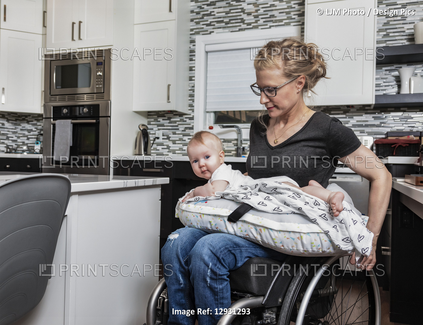 A paraplegic mother holding her baby on her lap, in her kitchen, while pushing ...