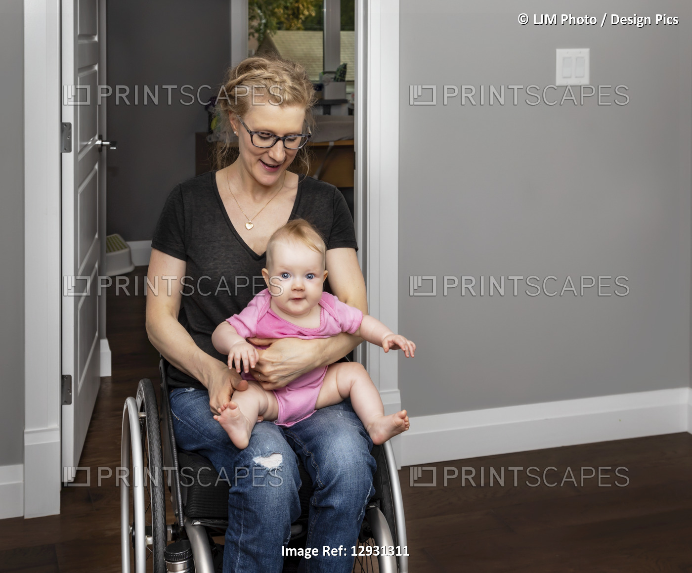 A paraplegic mother holding her baby on her lap while moving around her home in ...