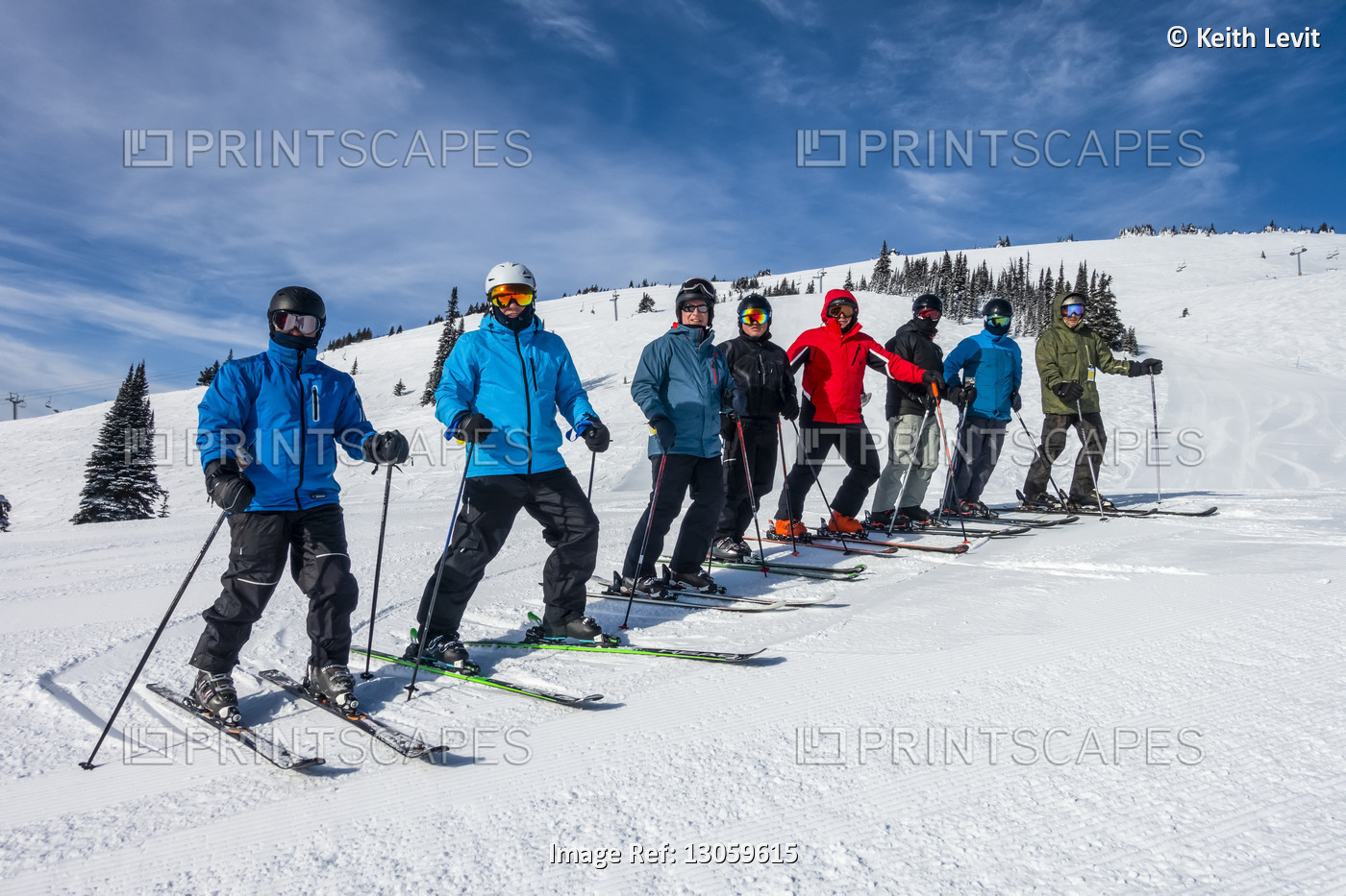 Downhill skiers standing in a row posing for the camera on a snowy slope; ...