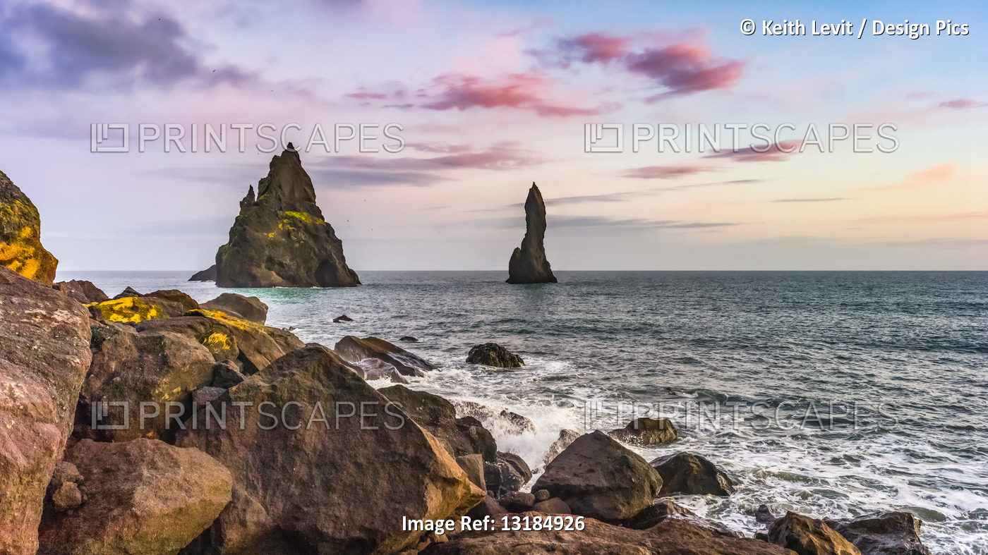 Sea stacks and tranquil ocean water along the coast of Southern Iceland; ...