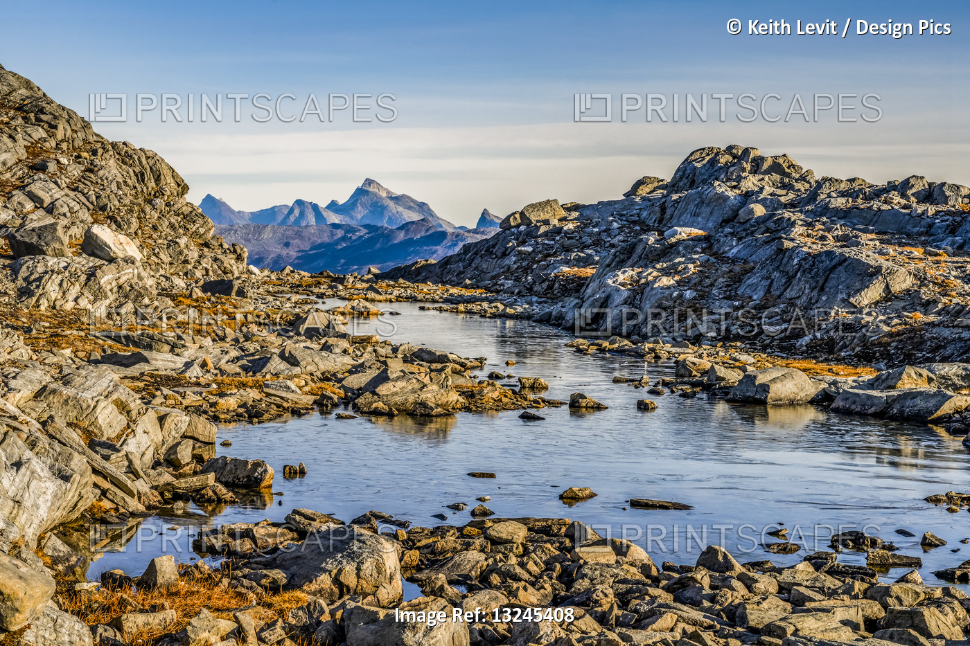 Rocky landscape with water and rugged mountain peaks in the distance; ...