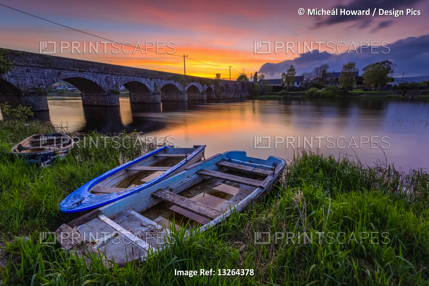 Two small wooden boats on the bank of the Shannon river in front of a stone ...