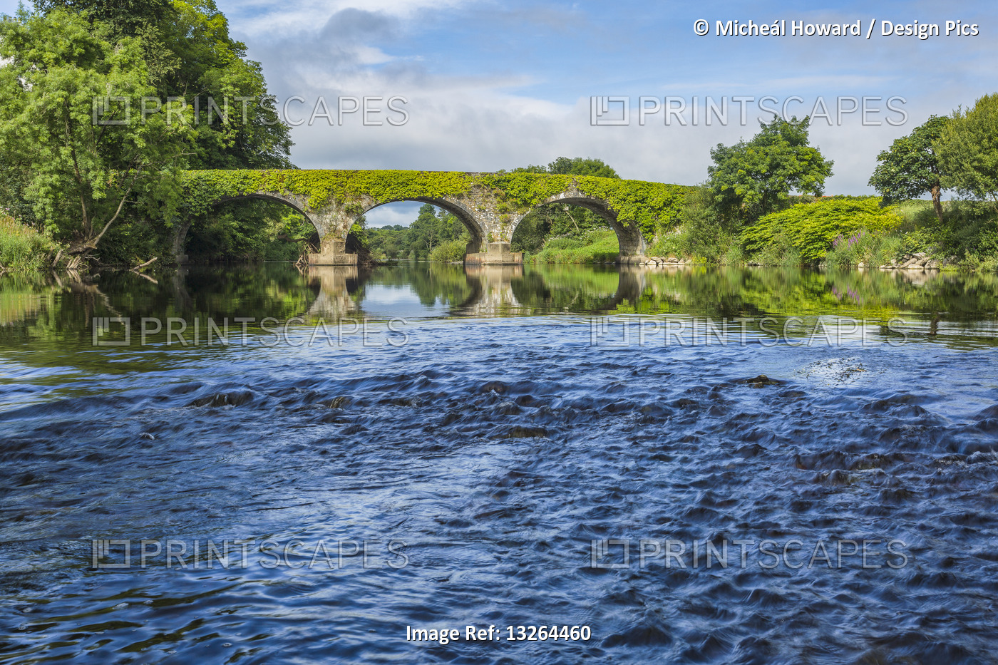 Small rapids on the Blackwater river with an old stone bridge in the background ...