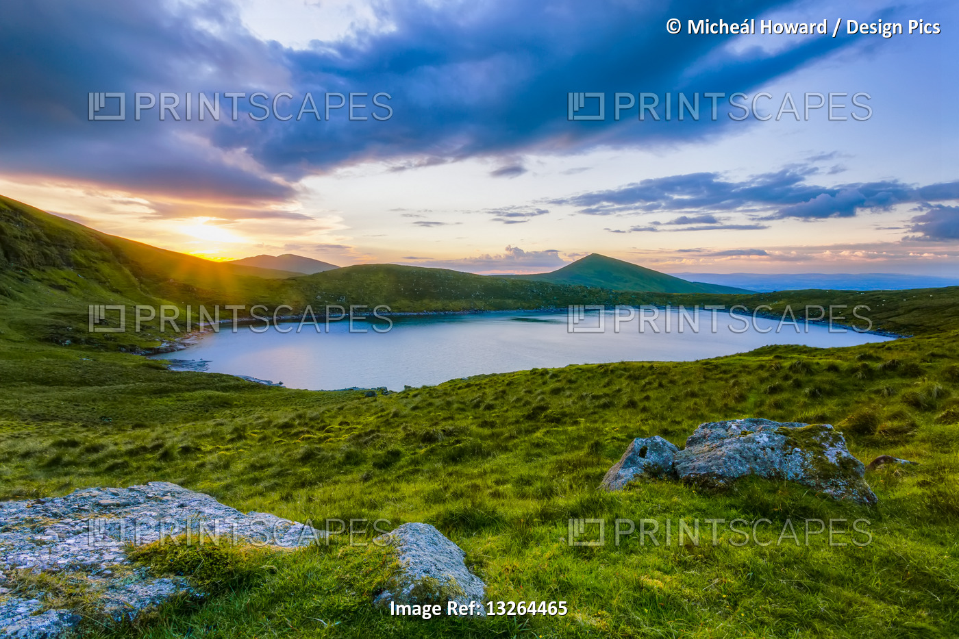 Sun setting over Lough Muskery in the Galty Mountains in summer with large ...