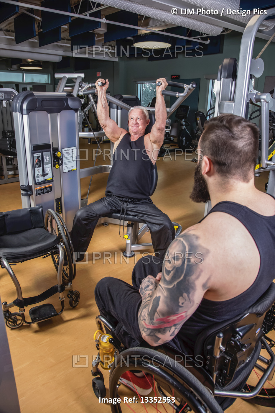 One paraplegic man working out using an overhead press in fitness facility ...