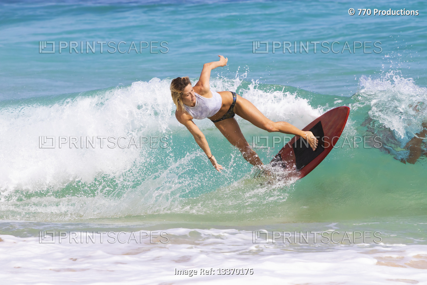 A young woman skimboarding on a wave off Sandy Beach, Oahu; Oahu, Hawaii, ...