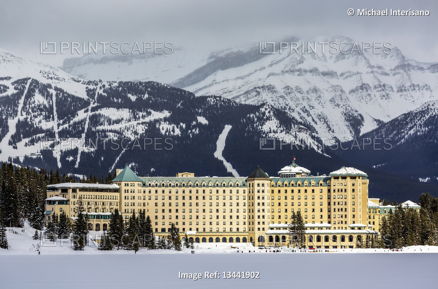 Large Chateau Hotel lit by the sun with a mountain ski hill in the background ...