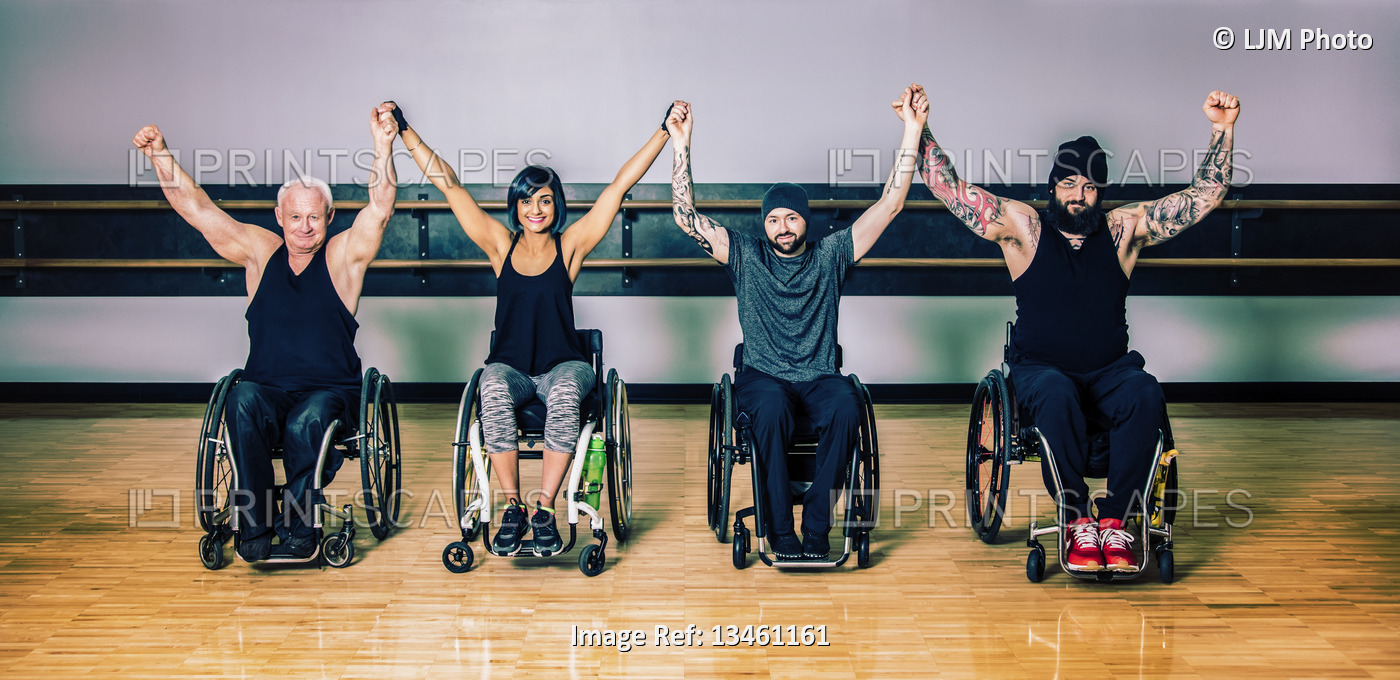 A group of paraplegic friends raising their hands together in victory after a ...