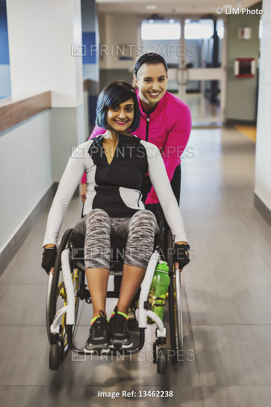 A paraplegic woman and her trainer pose for the camera while in a hallway in a ...