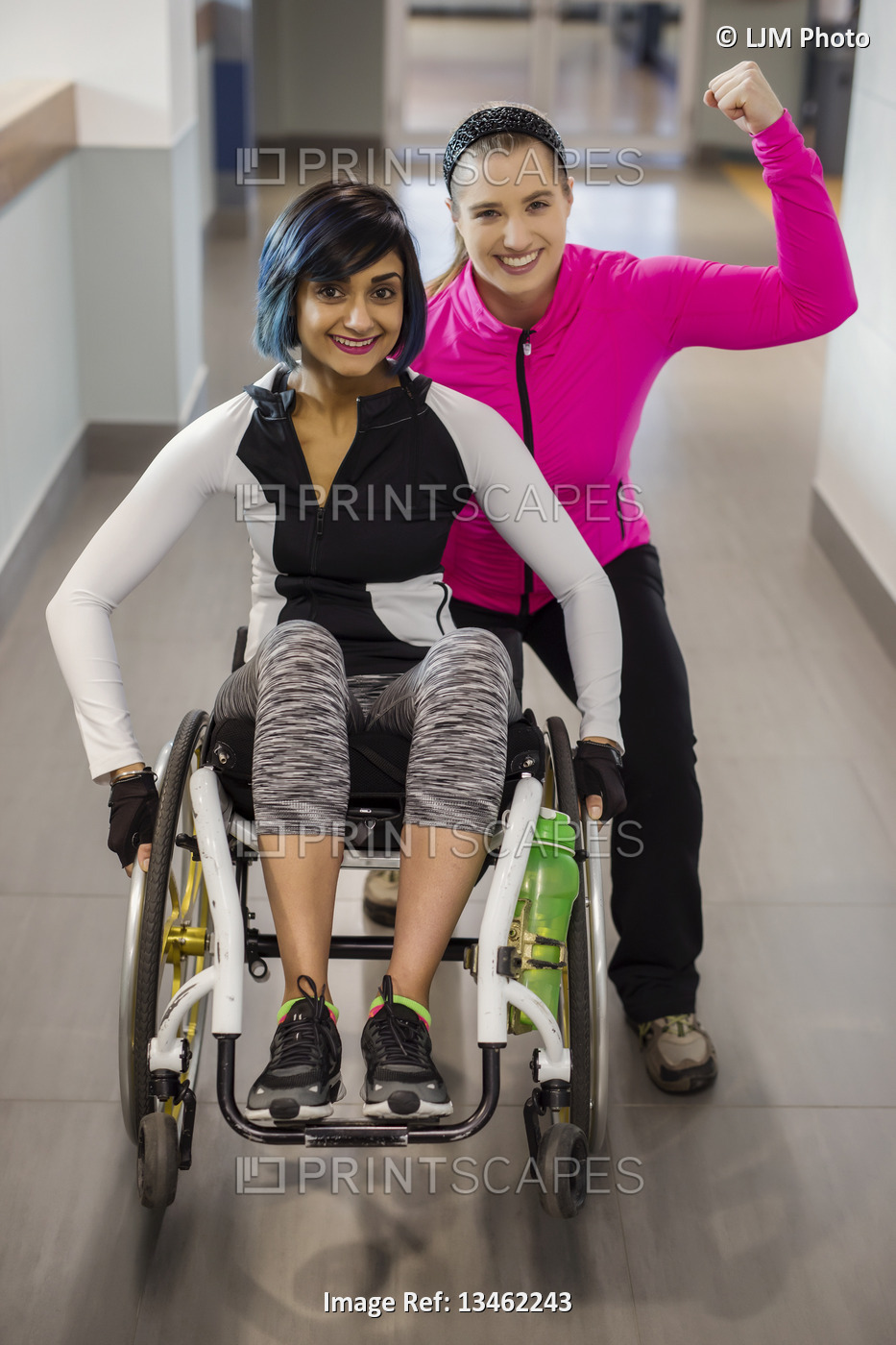 A paraplegic woman and her trainer pose for the camera while in a hallway in a ...