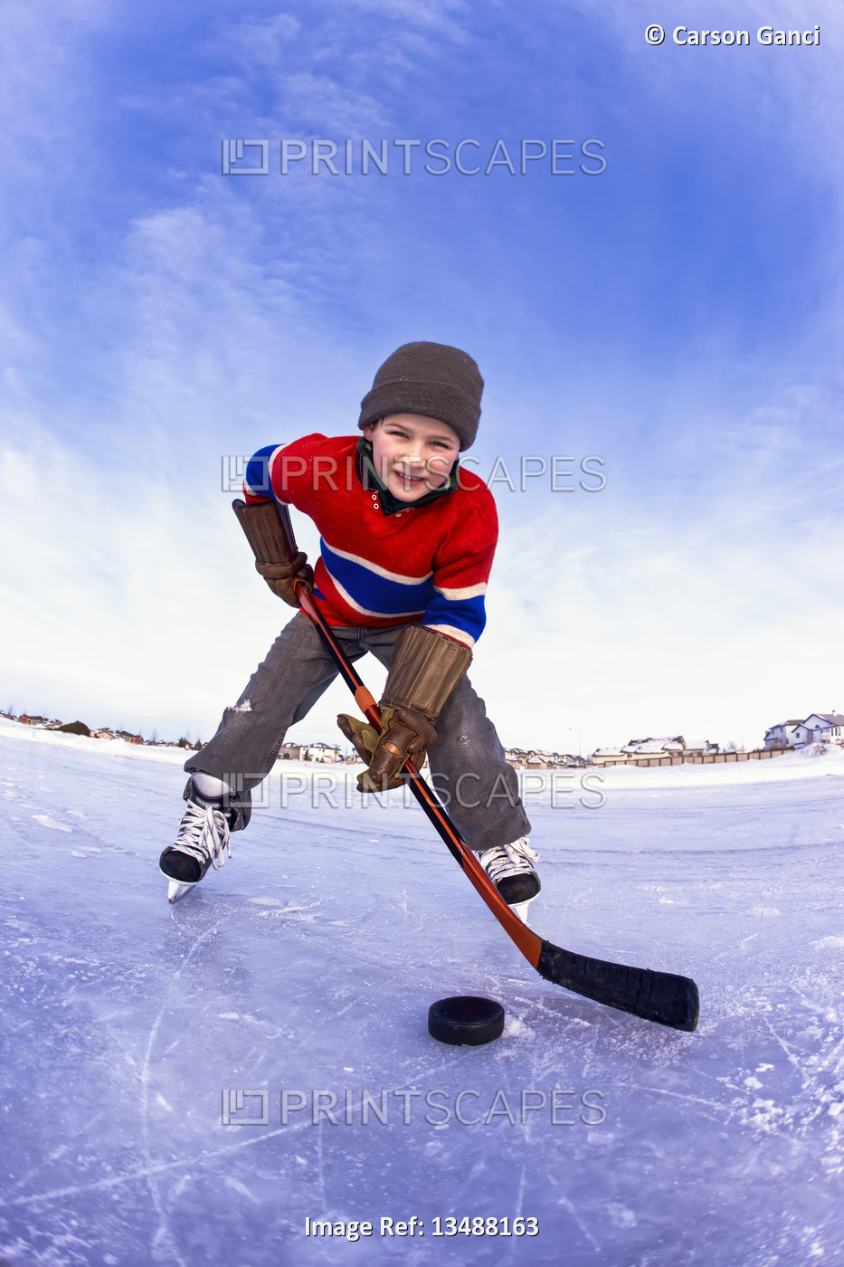 Young boy playing hockey outdoors on a frozen rink; Alberta, Canada