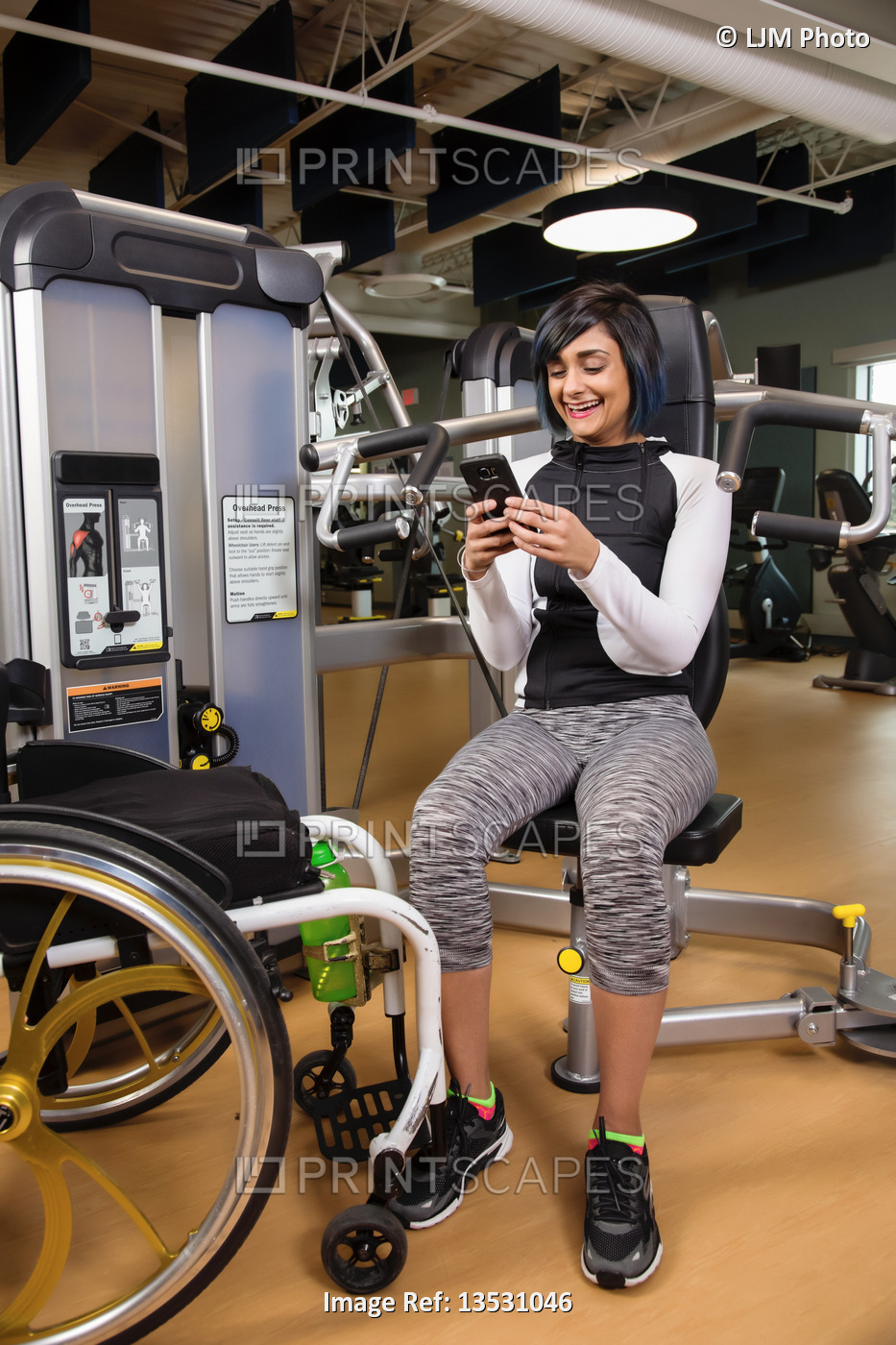 A paraplegic woman resting and texting on her smart phone after working out ...