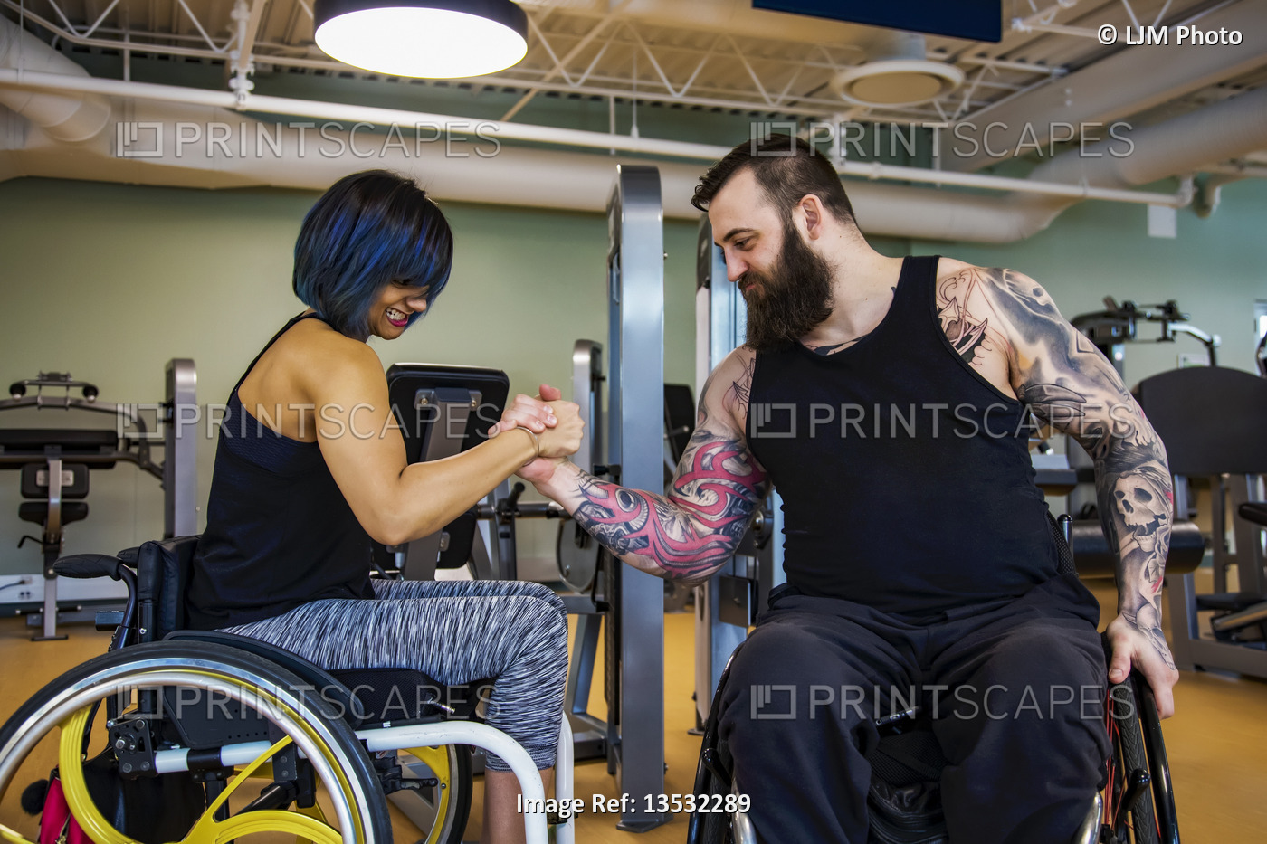 Two paraplegic friends pretending to arm wrestle after working out at a fitness ...