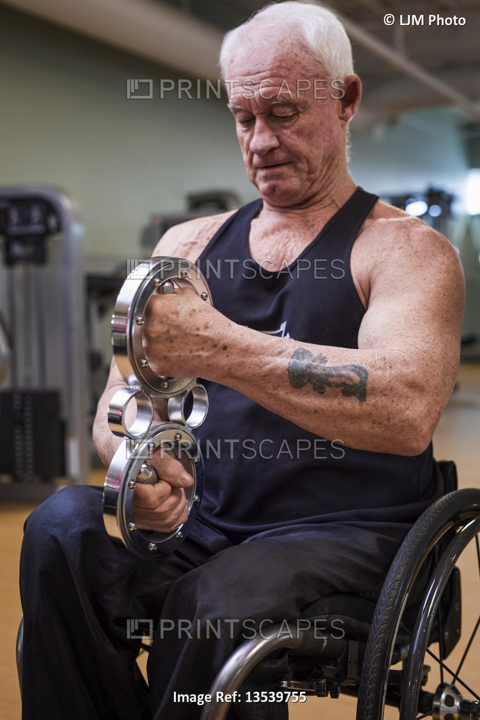 A senior paraplegic man working out using a circular handheld device in fitness ...