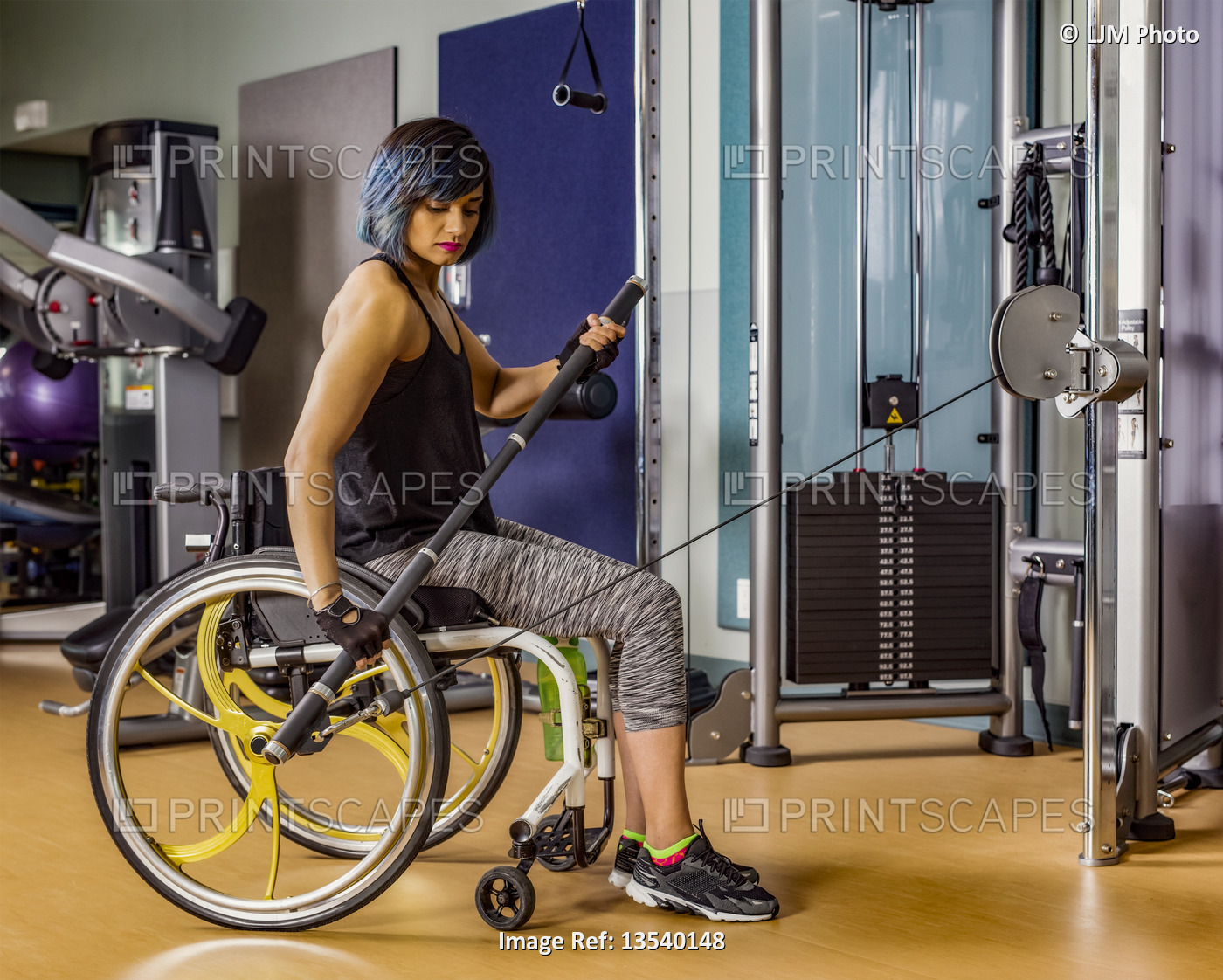 A view from the side of a paraplegic woman working out using a bar connected to ...