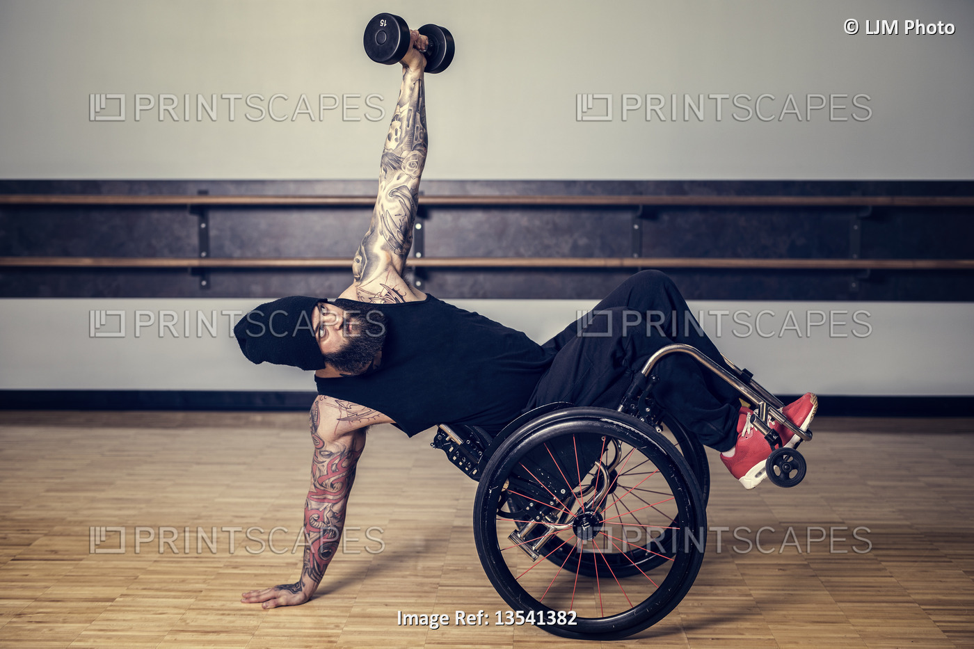 A paraplegic man popping a wheelie in his wheelchair and balancing while ...
