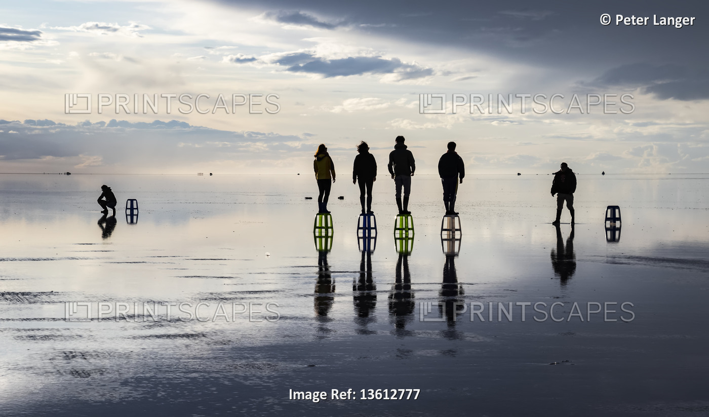 Tourists posing in the reflection during the wet season (December-February) in ...