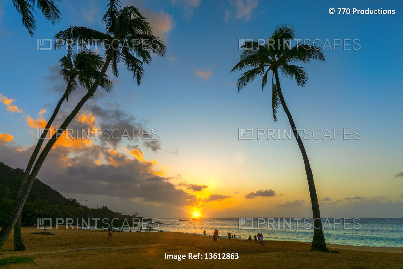 Tourists enjoying the beach at Waimea Bay Beach Park at sunset; Oahu, Hawaii, ...