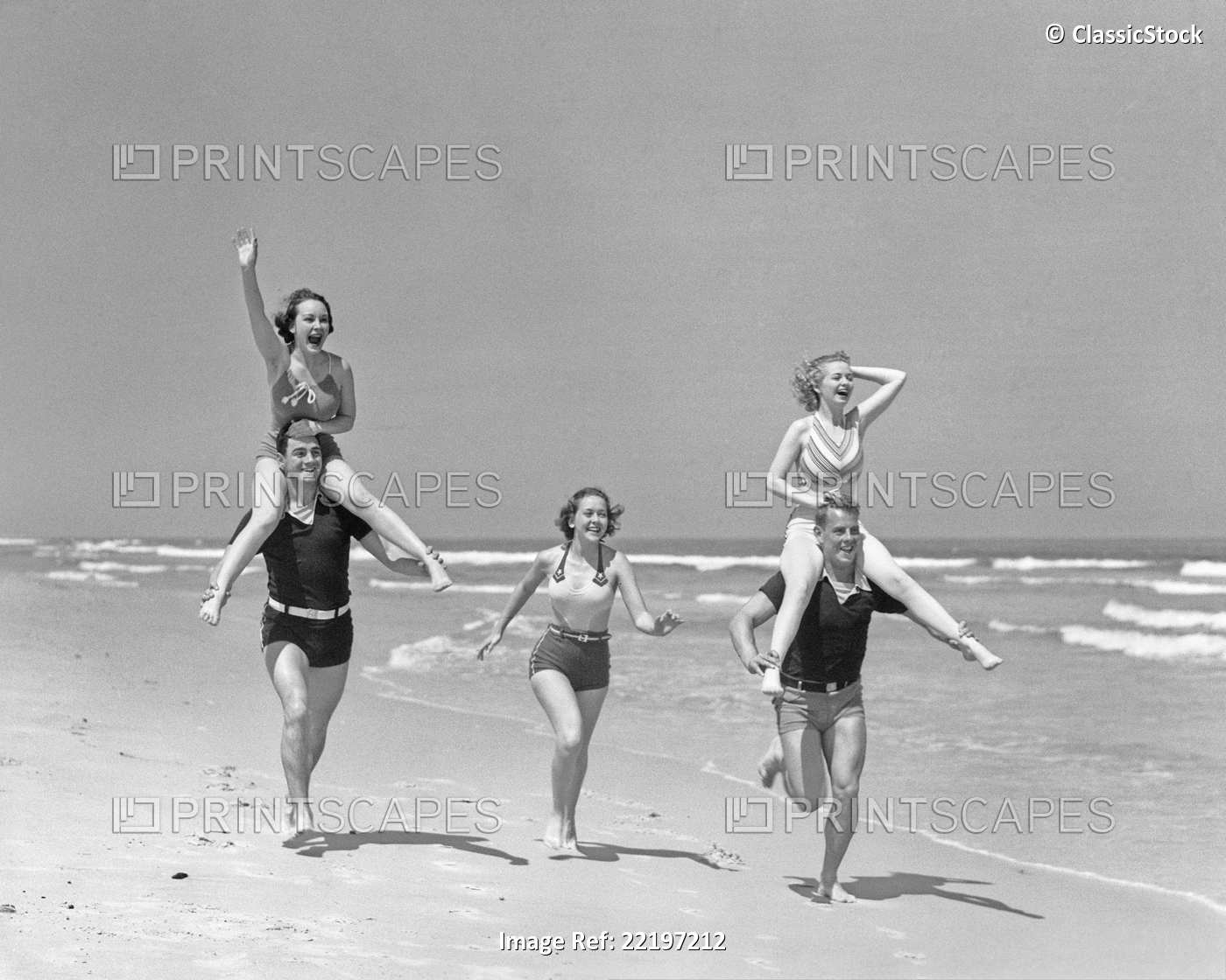 1930s GROUP MEN WOMEN RUNNIG FROLICKING ON BEACH WOMEN RIDING ON MENS SHOULDERS