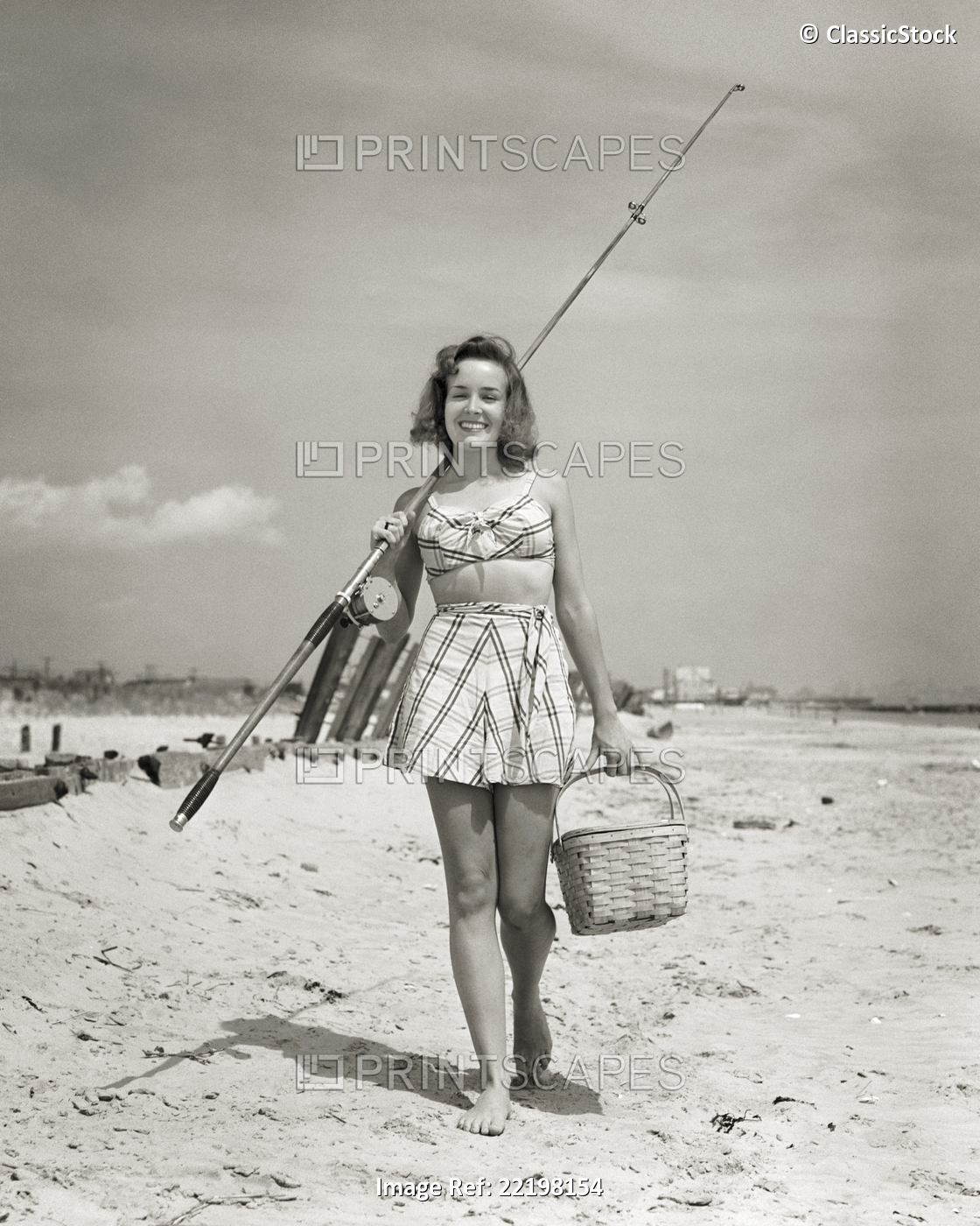 1940s SMILING YOUNG WOMAN WALKING ON BEACH LOOKING AT CAMERA WEARING TWO PIECE ...